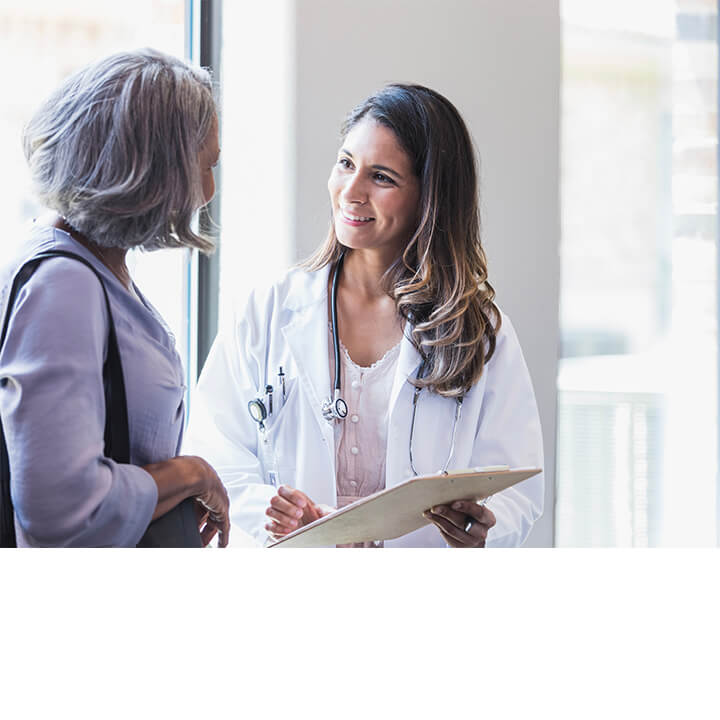 A nurse and an adult patient smiling and reviewing information on a clipboard