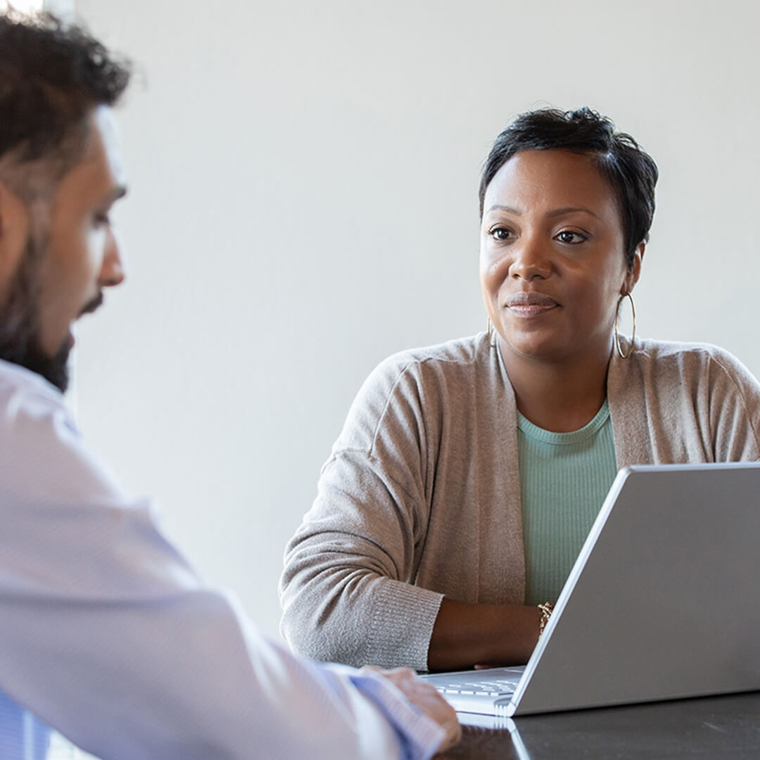 A cancer patient meets with a financial counselor in a bright office, receiving support