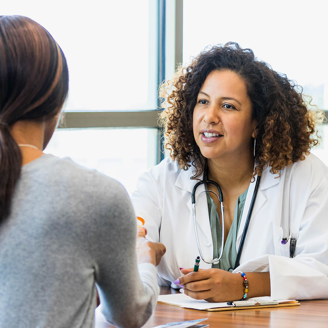 A woman and a doctor sit at a table, engaged in a discussion about navigating cancer treatment