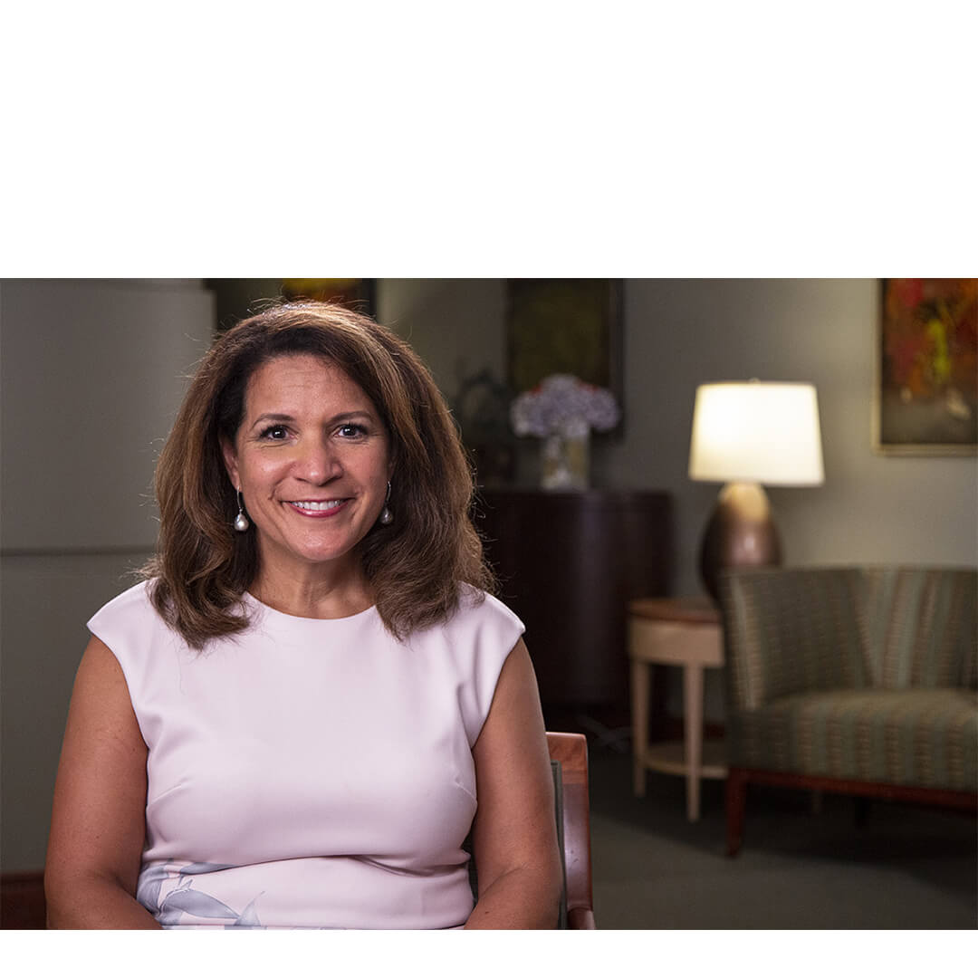 Ann Marie Wallace, smiling in a softly lit office setting, offers a warm and hopeful presence as a cancer patient advocate